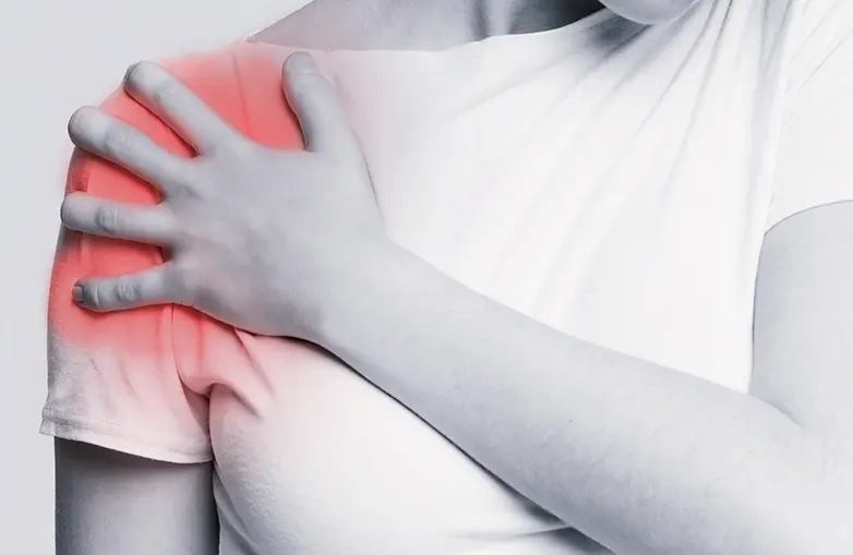 Photo of woman holding her shoulder in pain